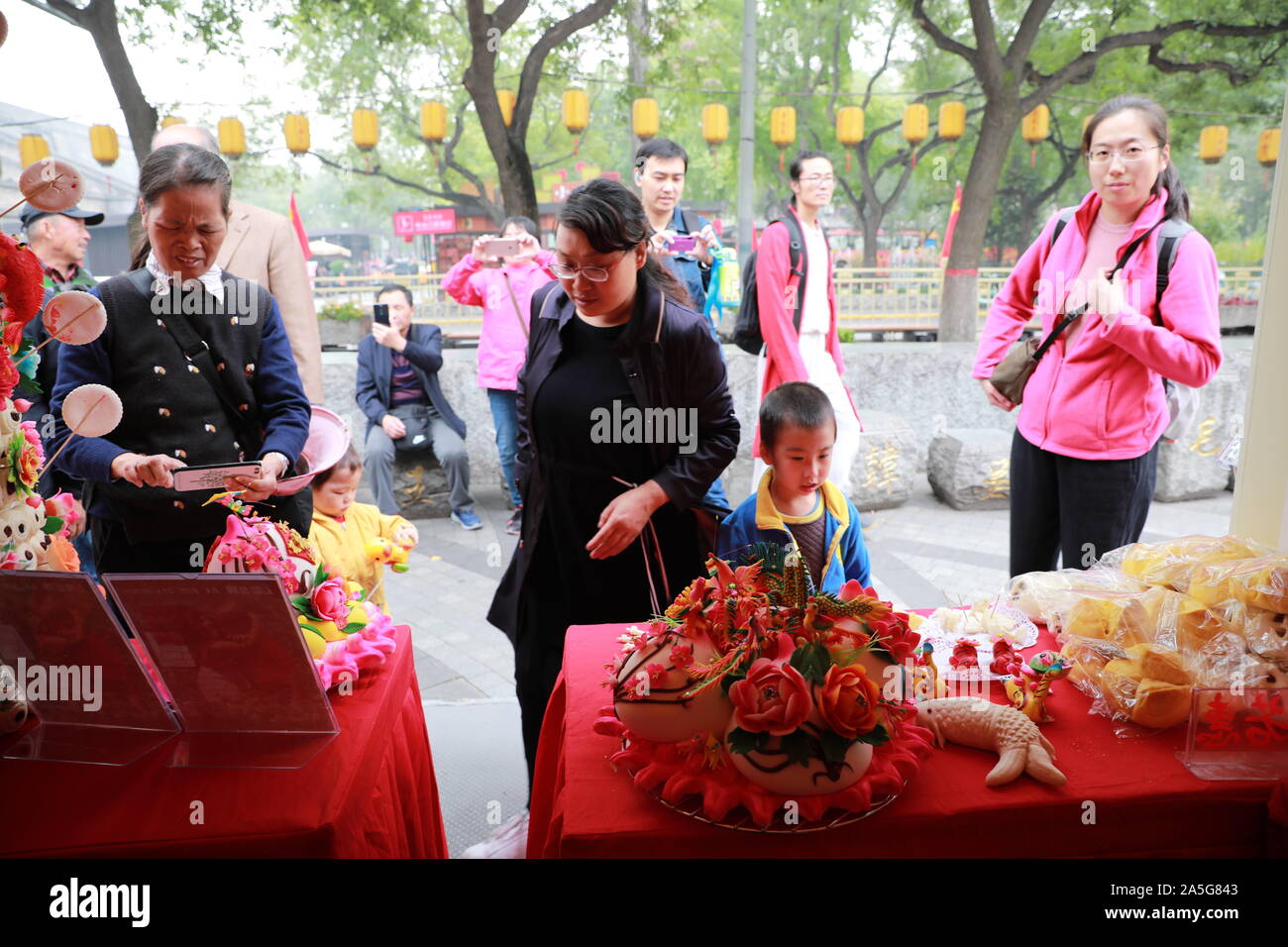 Shaanxi, China. 21st Oct, 2019. Chinese non-genetic artist Yue Ruohui from Xianyang, northwest China's Shaanxi province, creates coloured steamed bread, an art work, at the third Shaanxi folk art fair in Yongxing square, northwest China's xi 'an, Oct. 19, 2019.Her works not only symbolize prosperity brought by the dragon and the phoenix, having a surplus year after year, but also vivid images of tigers, roses, red carp and other children like lovely plants and animals, more lifelike peony bonsai, attracting passers-by. Credit: SIPA Asia/ZUMA Wire/Alamy Live News Stock Photo