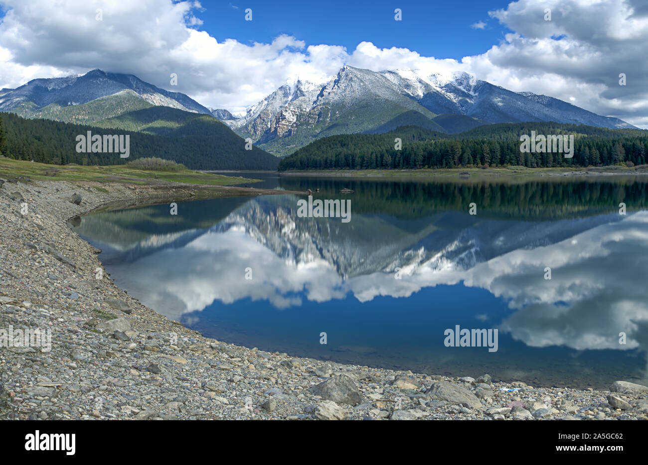 The calm still water of Mission reservoir and high peak snow covered