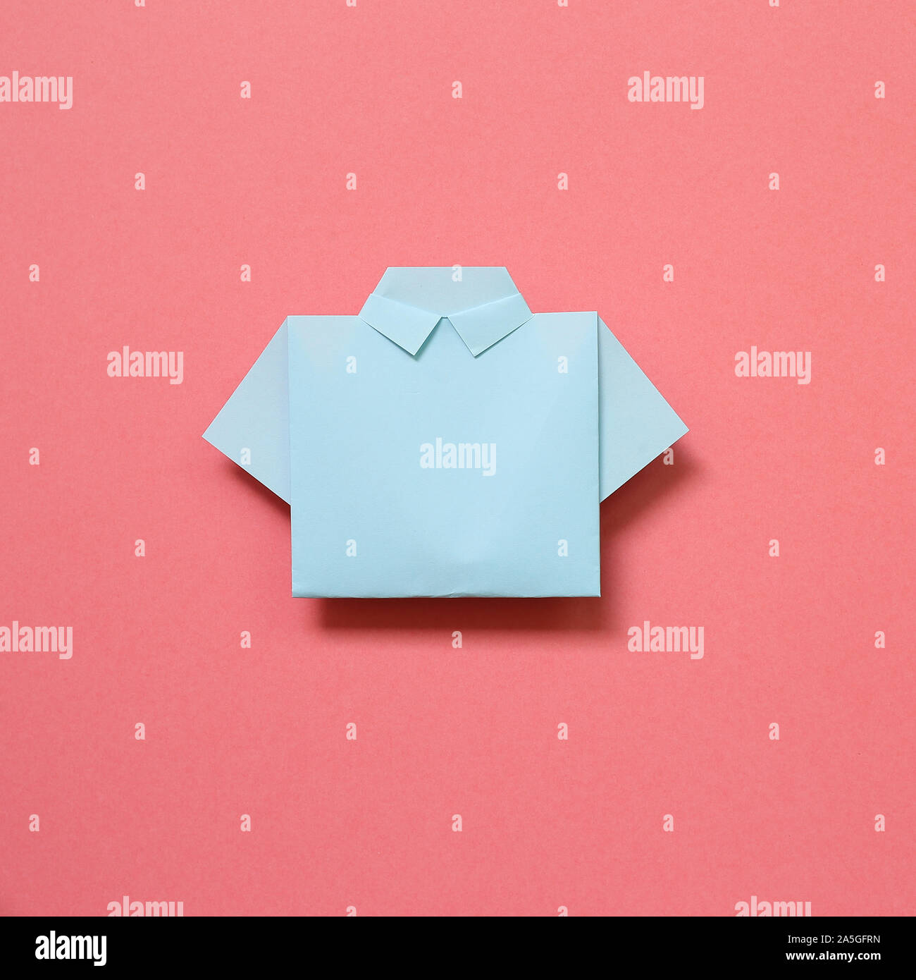 Blue paper shirt origami on pink background Stock Photo