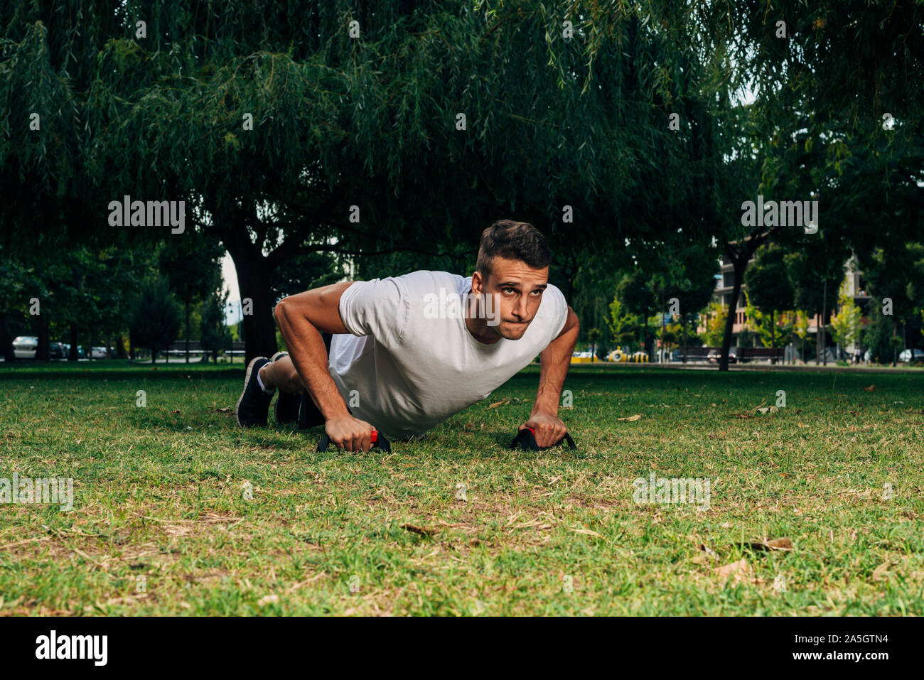 Man makes push ups at the park in summer as bodybulding exercise Stock ...