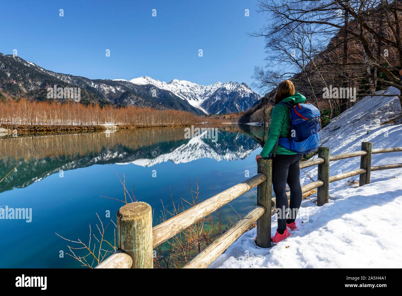 Young woman looking at sea, Japanese Alps reflected in Taisho Pond, Mount Hotaka in the back, Kamikochi, Matsumoto, Nagano Stock Photo