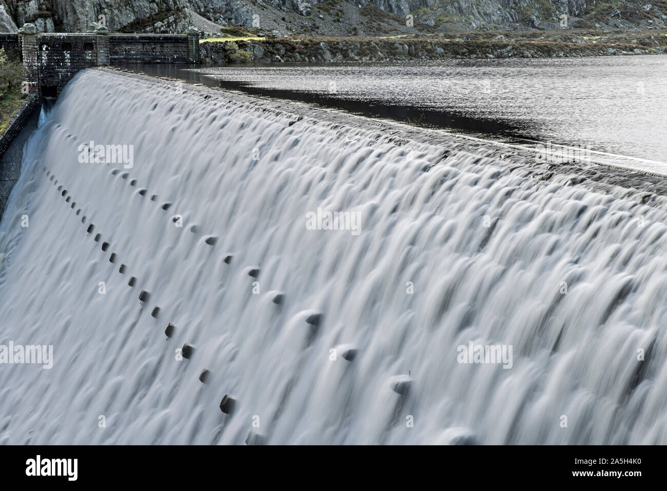 Caban Coch Dam in the Elan Valley Powys Mid Wales with water cascading over the lip after heavy rain. Stock Photo