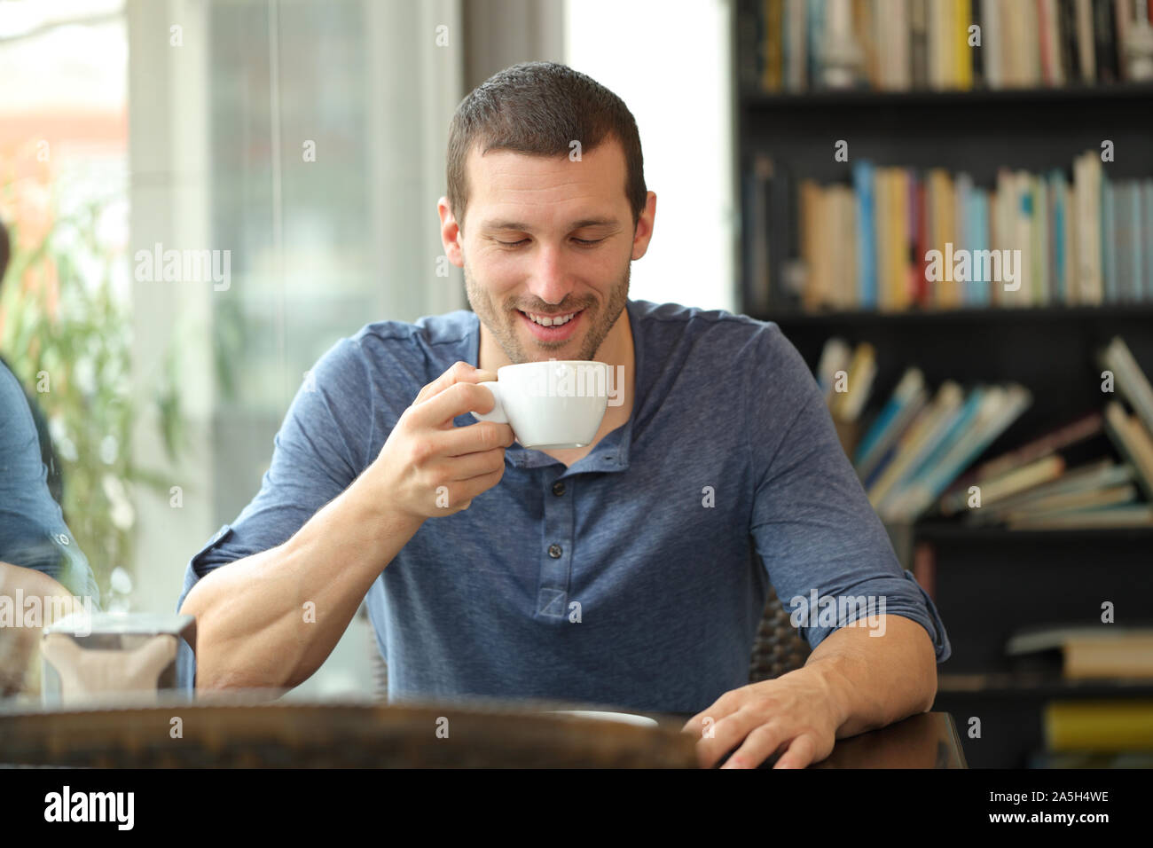 Front view of a happy man enjoying a cup of coffee sitting in a bar Stock Photo