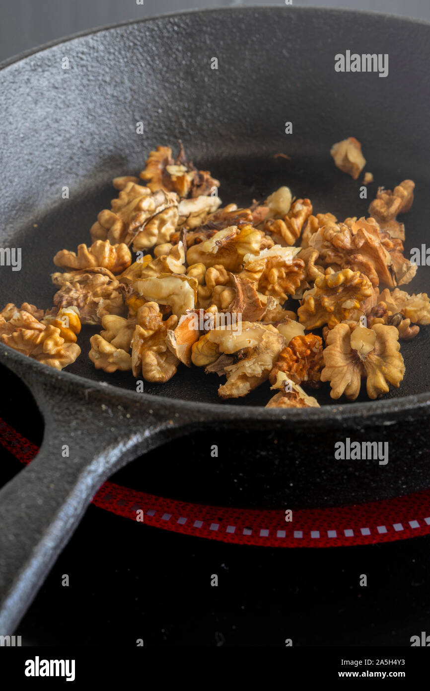 Walnuts Cooking In A Cast Iron Frying Pan On A Ceramic Hob Stove