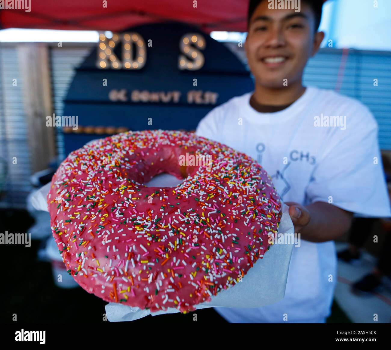Anaheim, USA. 20th Oct, 2019. A vendor shows a giant donut at the Donut Festival Orange County held in Anaheim, the United States, Oct. 20, 2019. People enjoyed different kinds of donuts and drinks at the festival held on Sunday. Credit: Li Ying/Xinhua/Alamy Live News Stock Photo