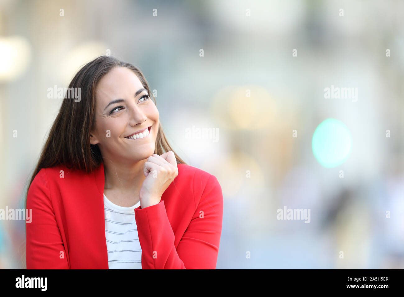 Candid woman thinking looking at side in the street with copy space Stock Photo