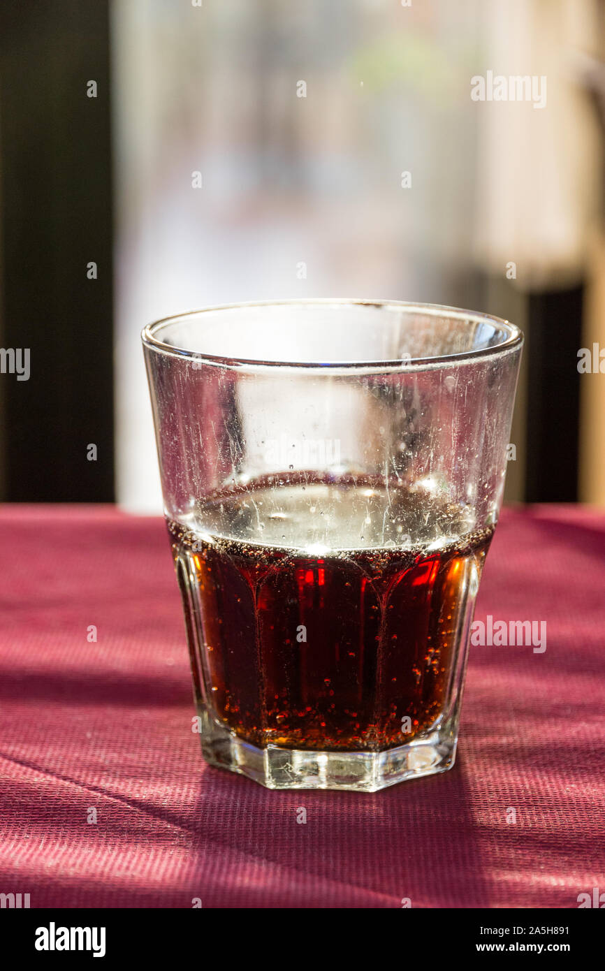 A beautifully backlit glass of red soft drink on a restaurant table in