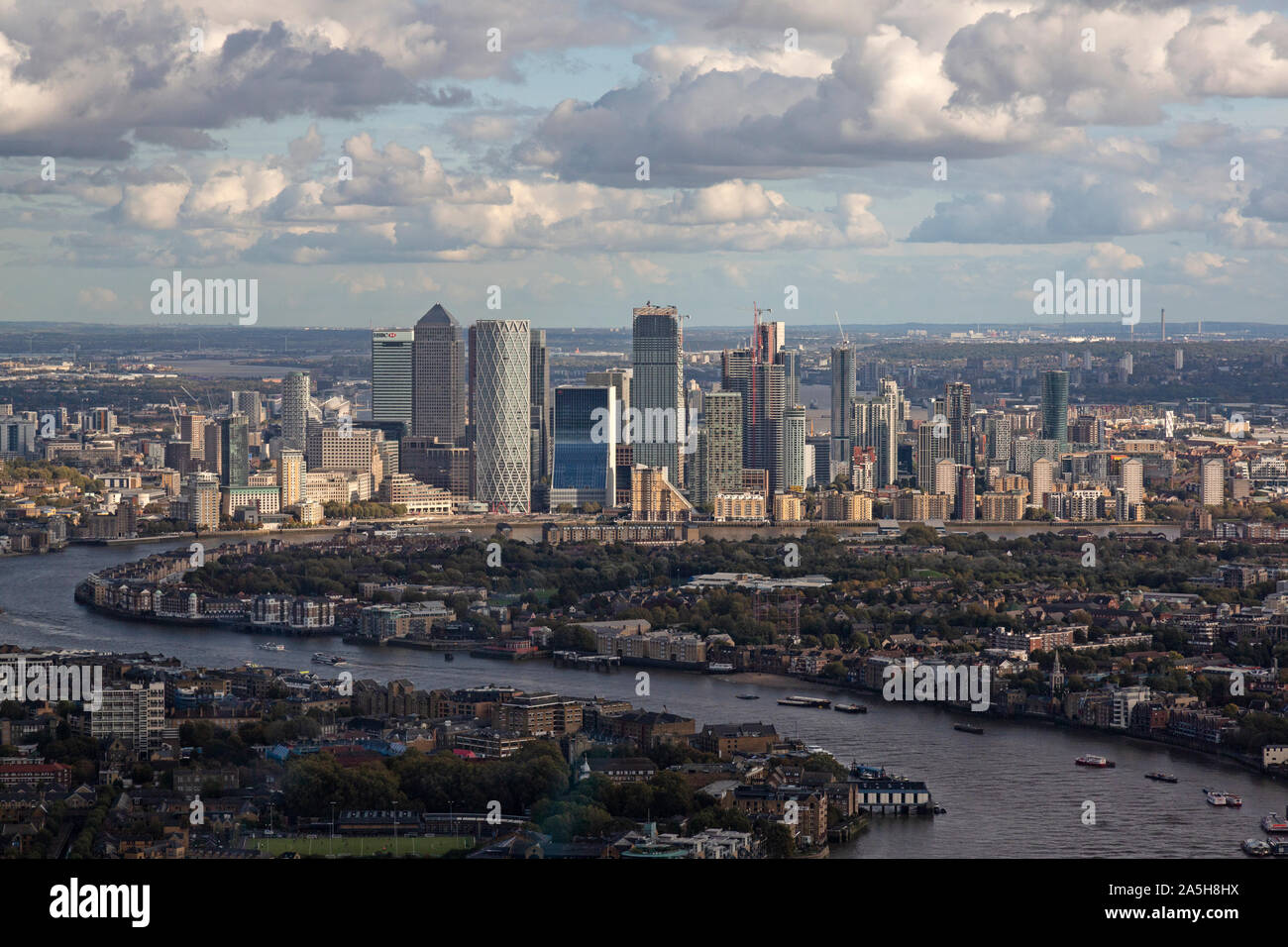 An aerial view looking east up the River Thames in London, with the buildings of Canary Wharf on the skyline. Stock Photo