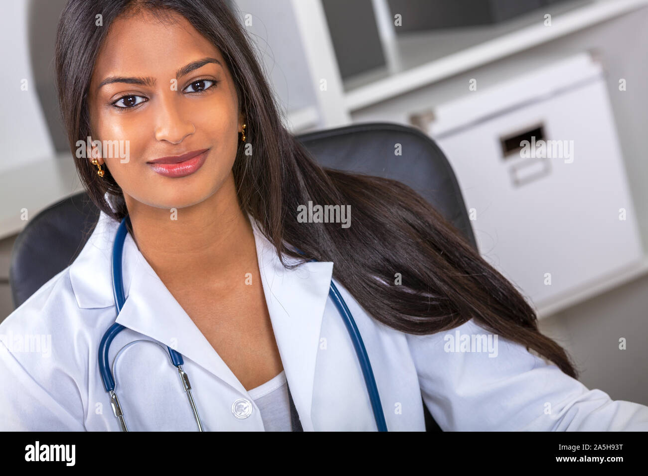 Indian Asian female medical doctor in a hospital office happy and smiling with stethoscope Stock Photo