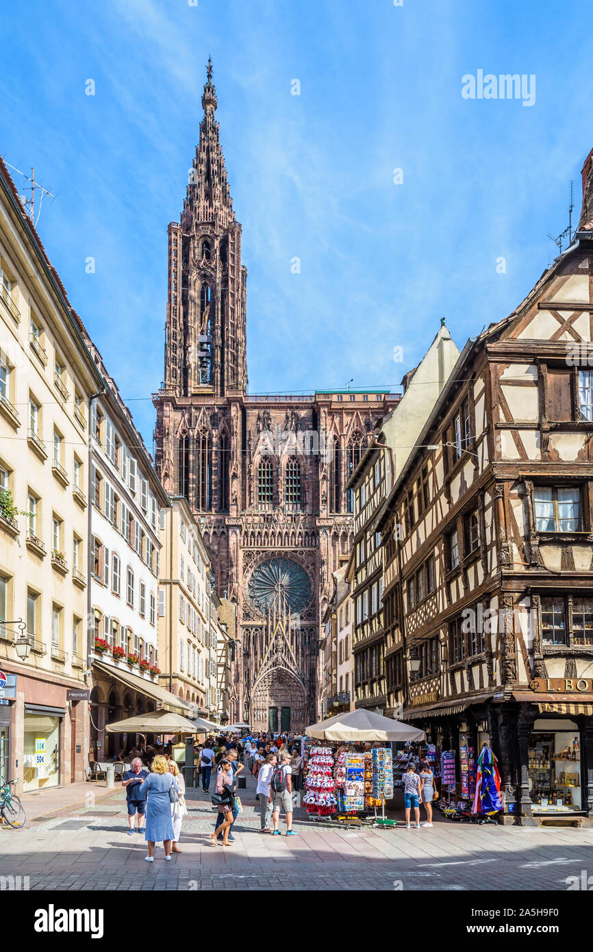 Facade of Notre-Dame cathedral in Strasbourg, France, seen from the busy Merciere street lined with half-timbered townhouses in the historic center. Stock Photo