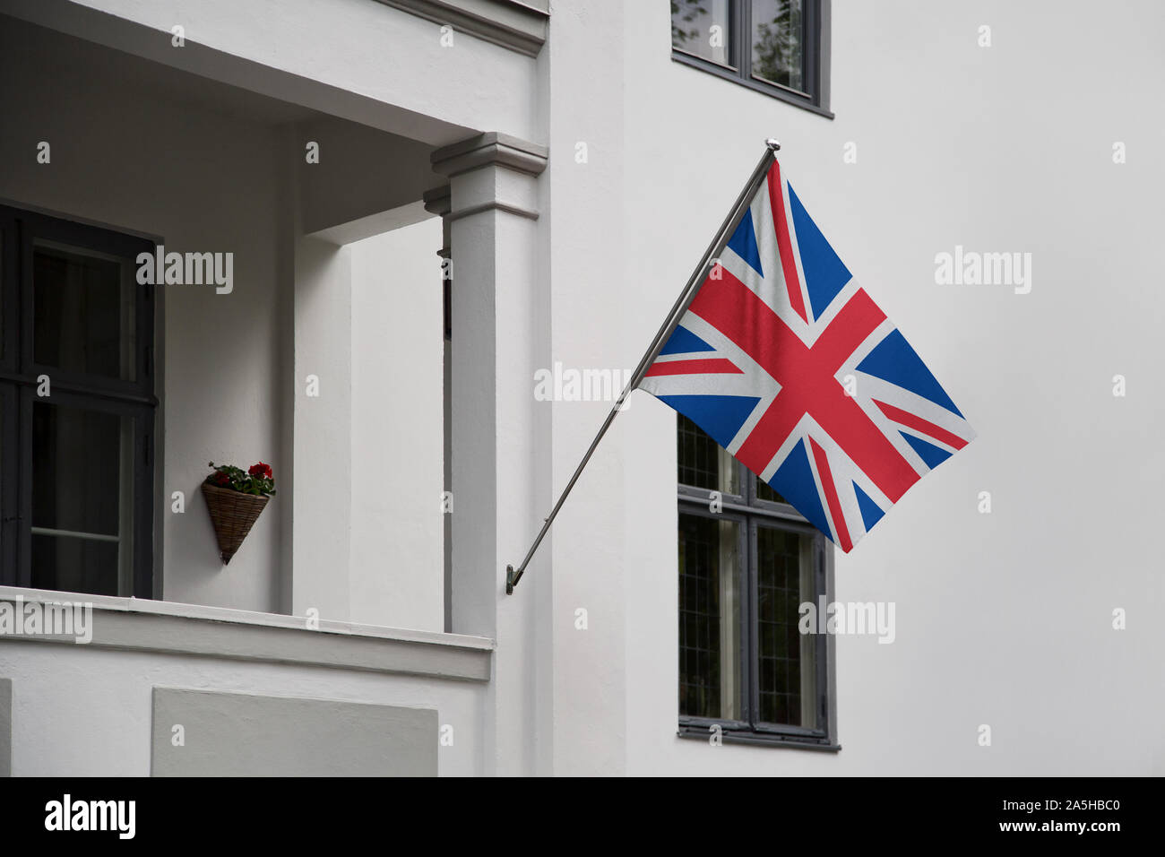 UK flag. British Union Jack flag displaying on a pole in front of the house. National flag of Great Britain waving on a home hanging from a pole Stock Photo