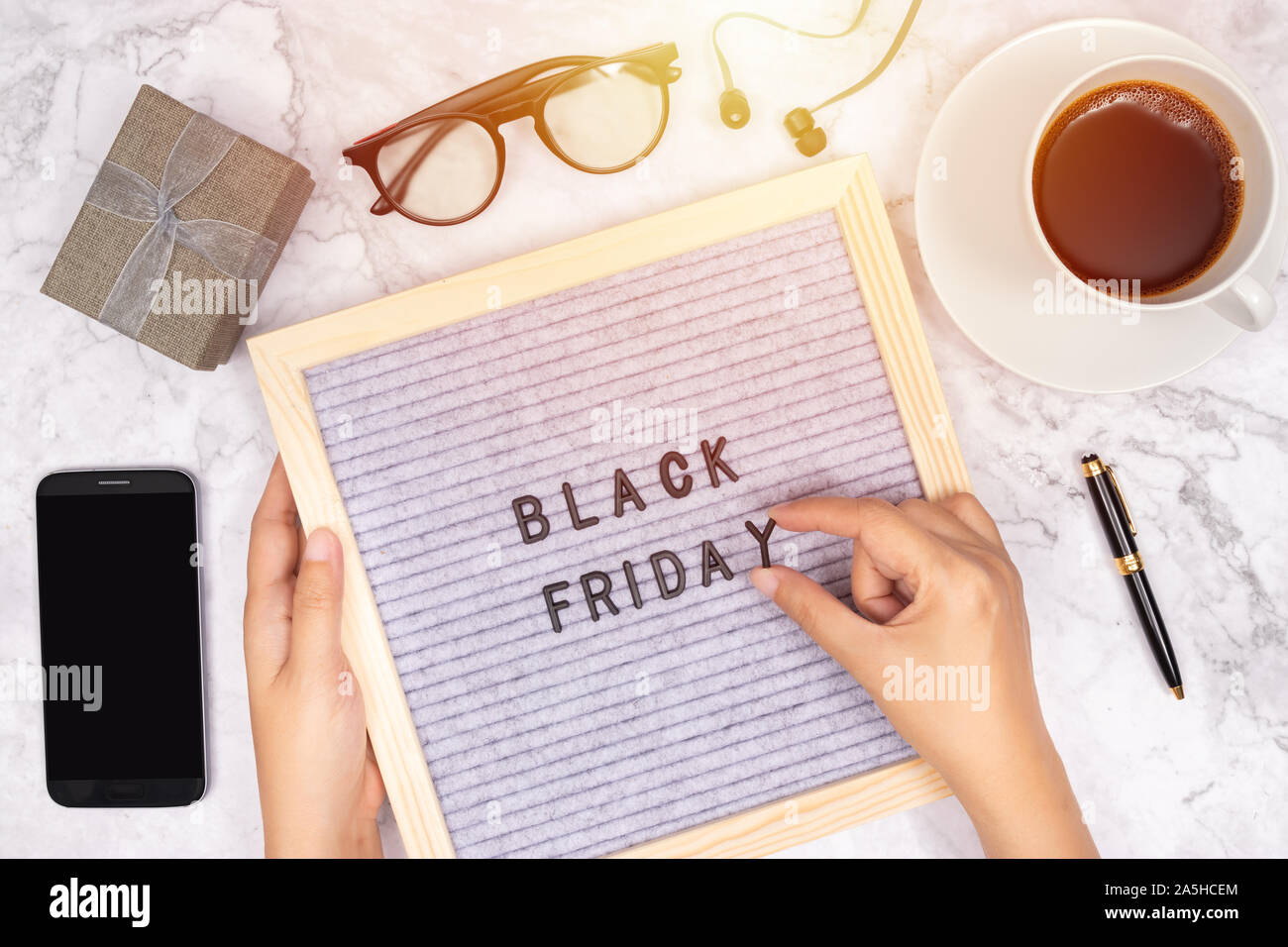 word Black Friday on letter board on white marble desk background with coffee cup ,gift box and smart phone with blank screen Stock Photo