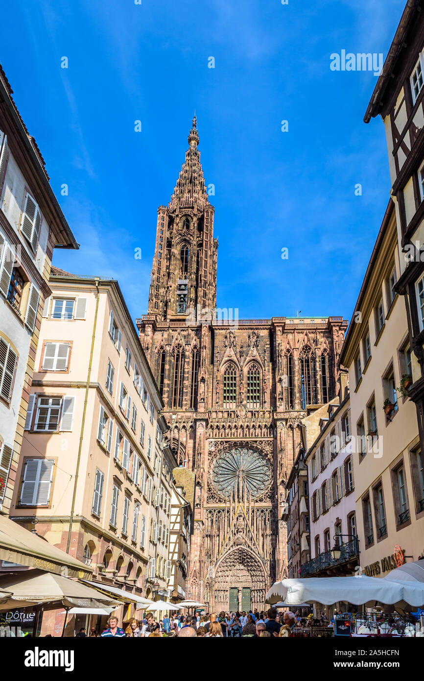 The facade of Notre-Dame cathedral in Strasbourg, France, illuminated by the sun, seen from the busy Merciere street lined with old townhouses. Stock Photo