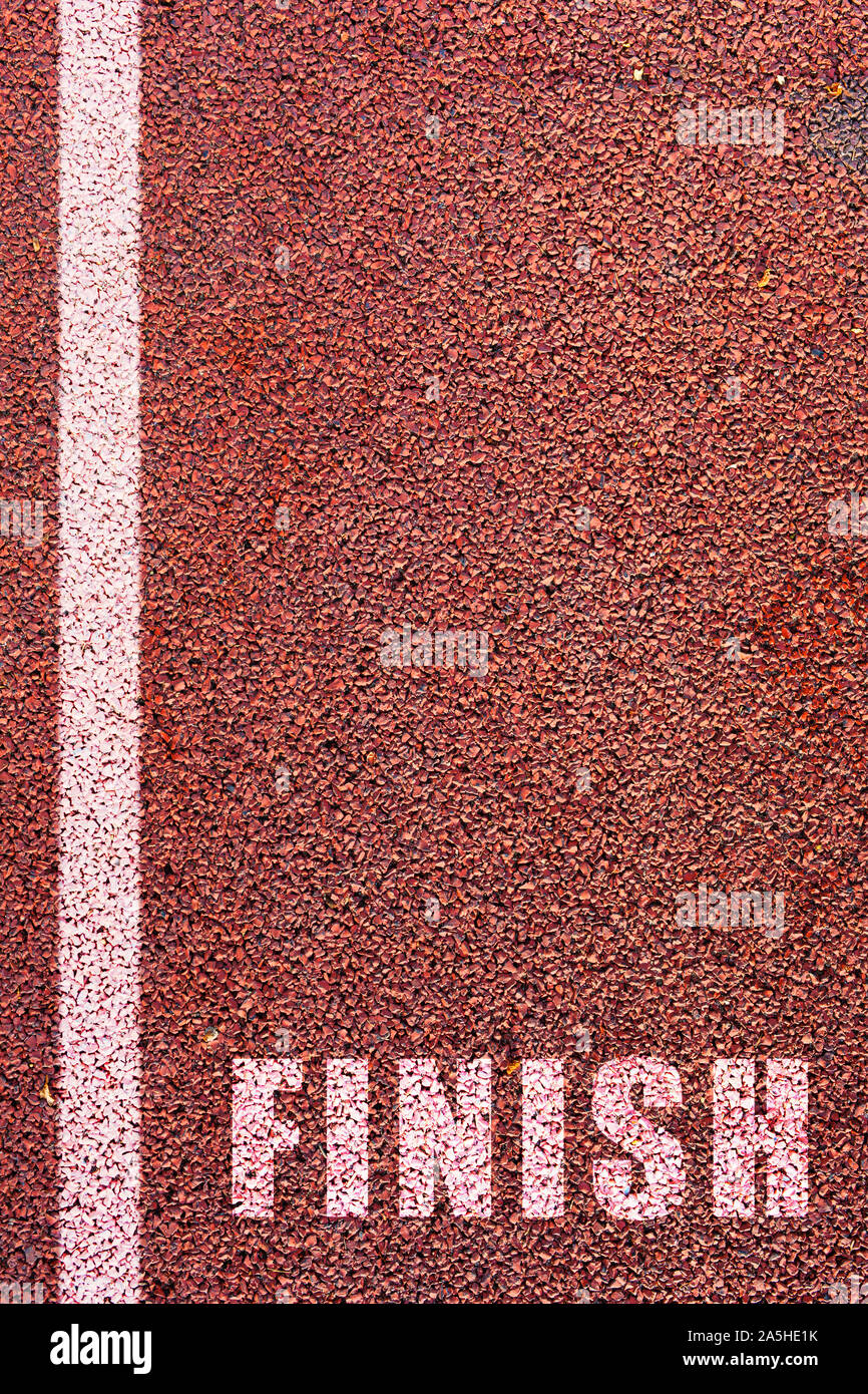 Concept for completion of a task or reaching goals. Finish line on athletics rubber running track background. Run to the finish line. Stock Photo