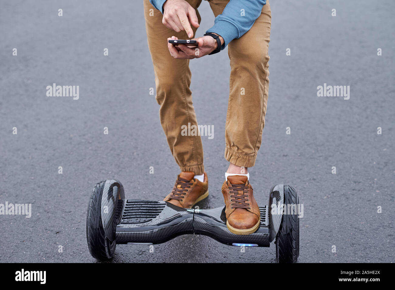 Smartphone in hands with application for electrical gyro scooter. Man use hoverboard outdoor Stock Photo
