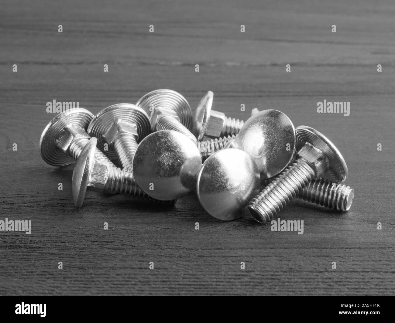 Set of steel screws on brown background in black and white color Stock Photo