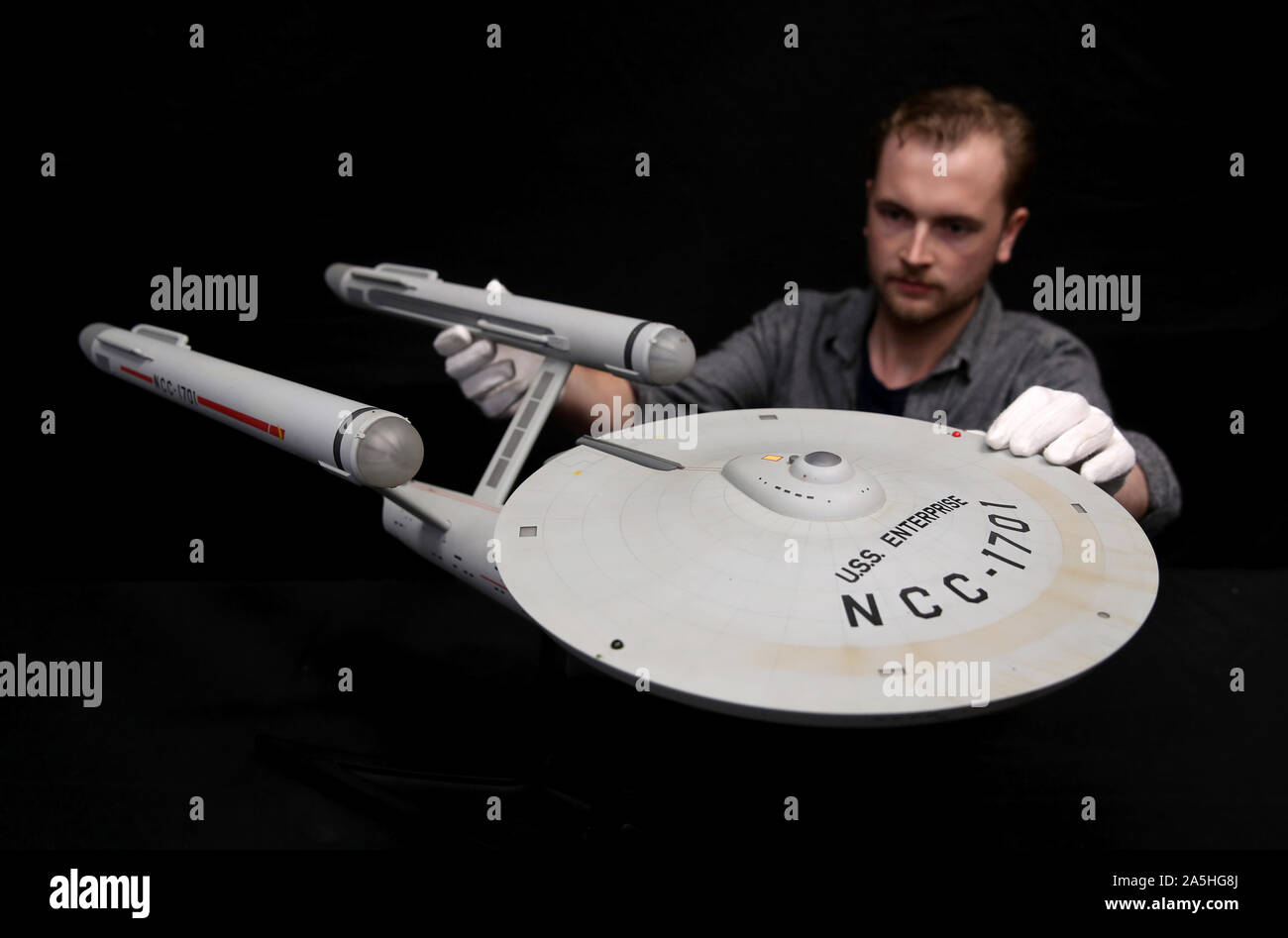 EMBARGOED TO 0001 TUESDAY OCTOBER 22 A Prop Store employee inspects a model replica of the USS Enterprise NCC-1701 from Star Trek: The Original Series (estimate £1,000 - £2,000), during a preview for the Prop Store's forthcoming cinema poster live auction. Stock Photo