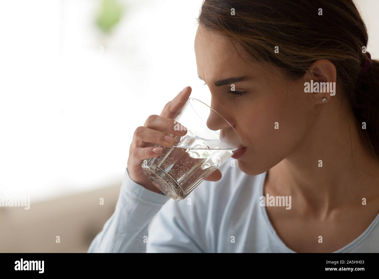 Close up young mixed race woman drinking glass of water. Stock Photo