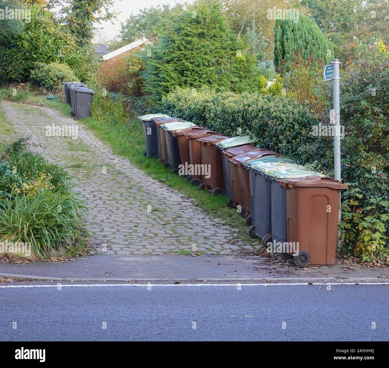 Green and Brown wheelie bins wait to be emptied in New Mills, Derbyshire. Stock Photo