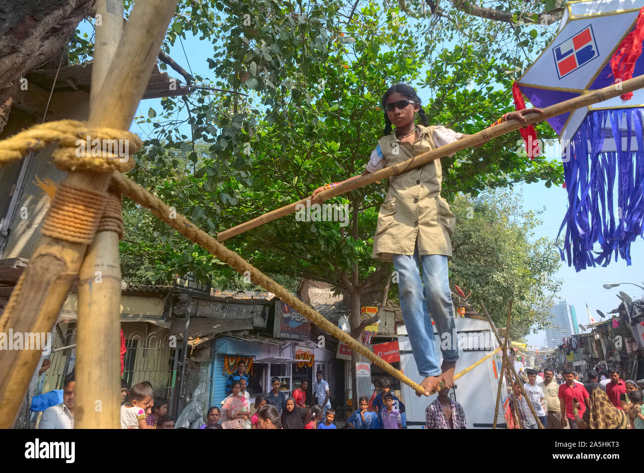 A girl in Mumbai, India performing a balancing act in a 'tamasha' or street circus, the sunglasses intransparent, so as to increase the difficulty Stock Photo