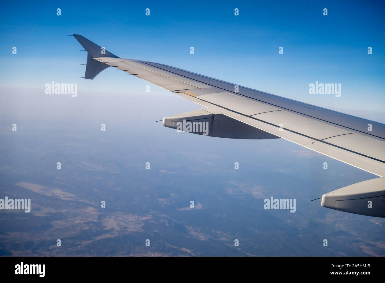 Looking through aircraft window during flight. Aircraft wing over blue skies and pyrenees mountains.Copy space. Stock Photo