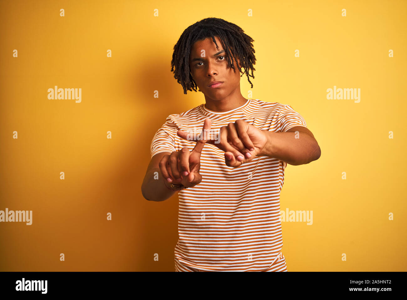 Afro man with dreadlocks wearing striped t-shirt standing over isolated ...