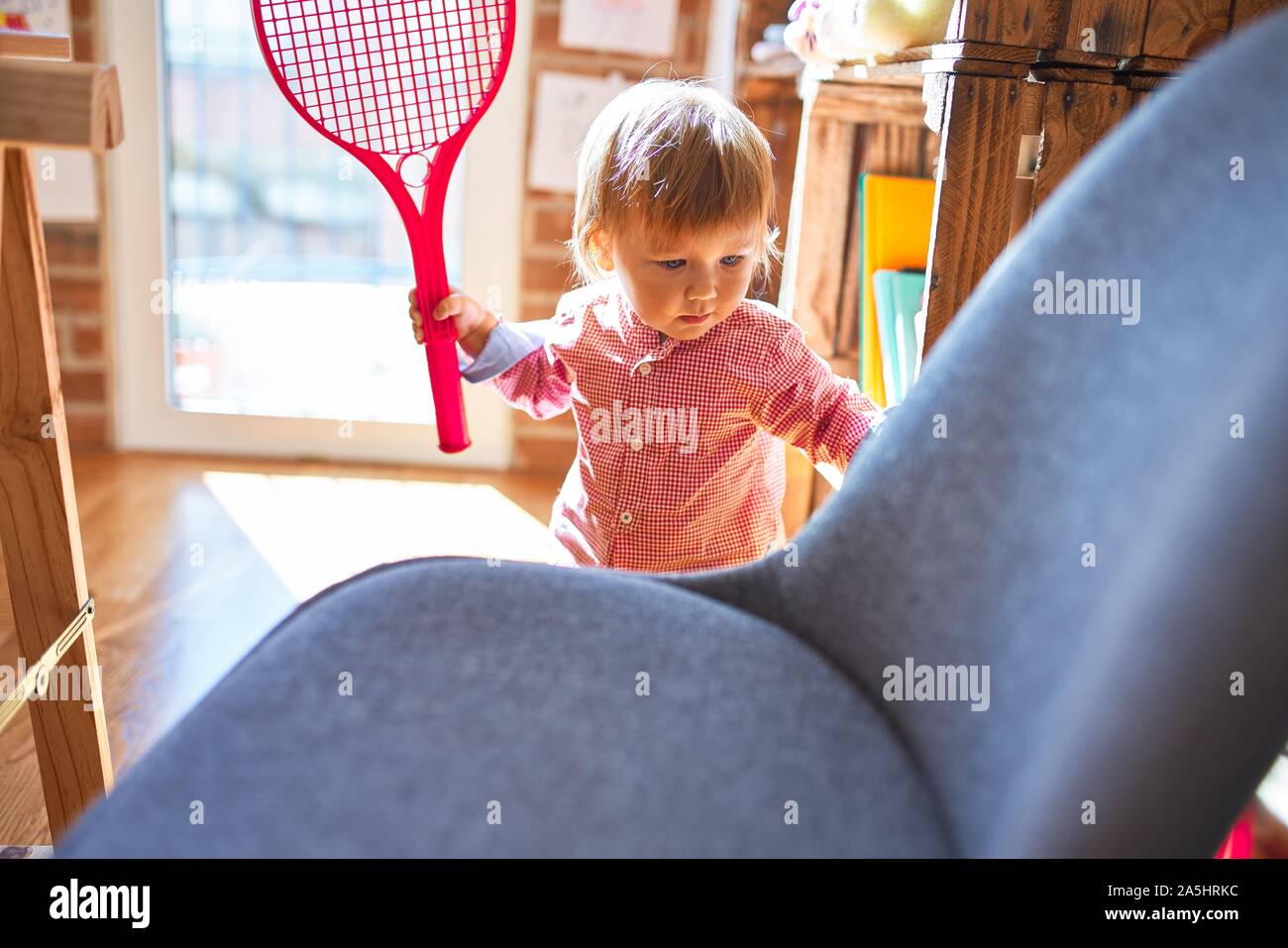 Adorable toddler smiling happy playing with tennis racket around lots ...