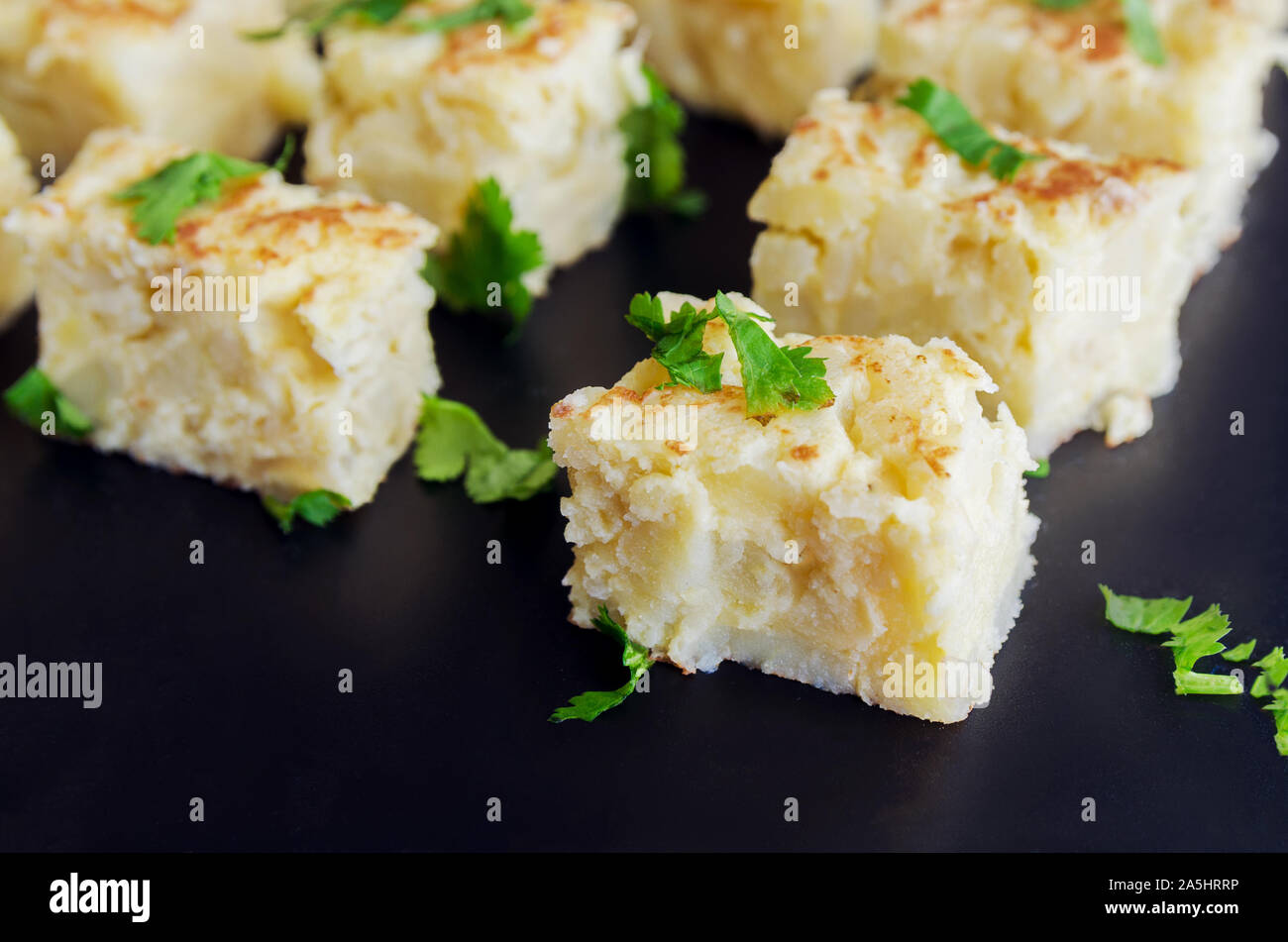 Pinchos  de  Tortilla, Spanish omelette made with eggs and potatoes. Traditional Spanish tapas or snack  on black bacground. Stock Photo