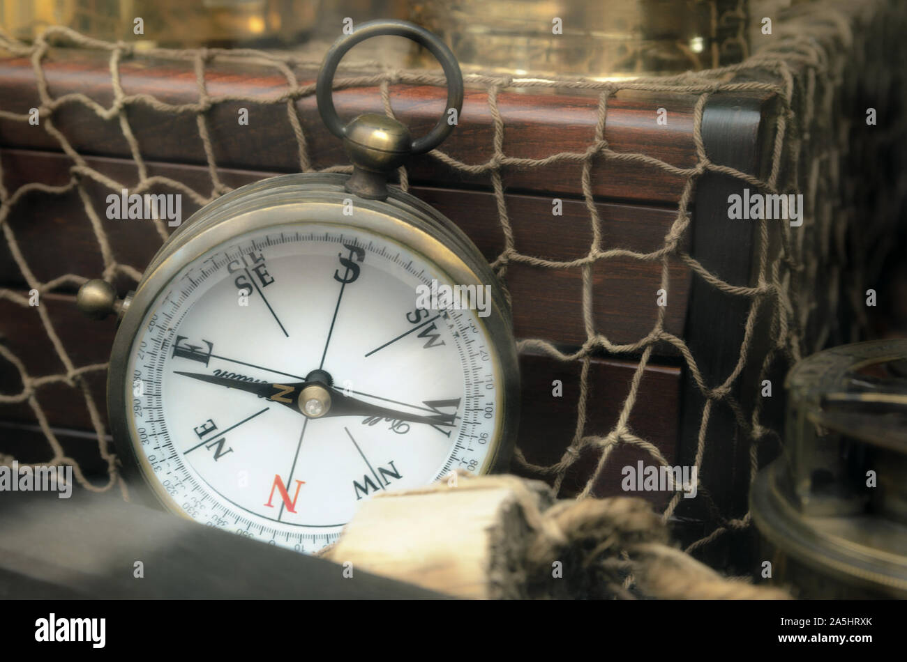 Vintage navigation compass standing upright on old treasure chest  with netting. Adventure and travel concept background.  Copy space Stock Photo