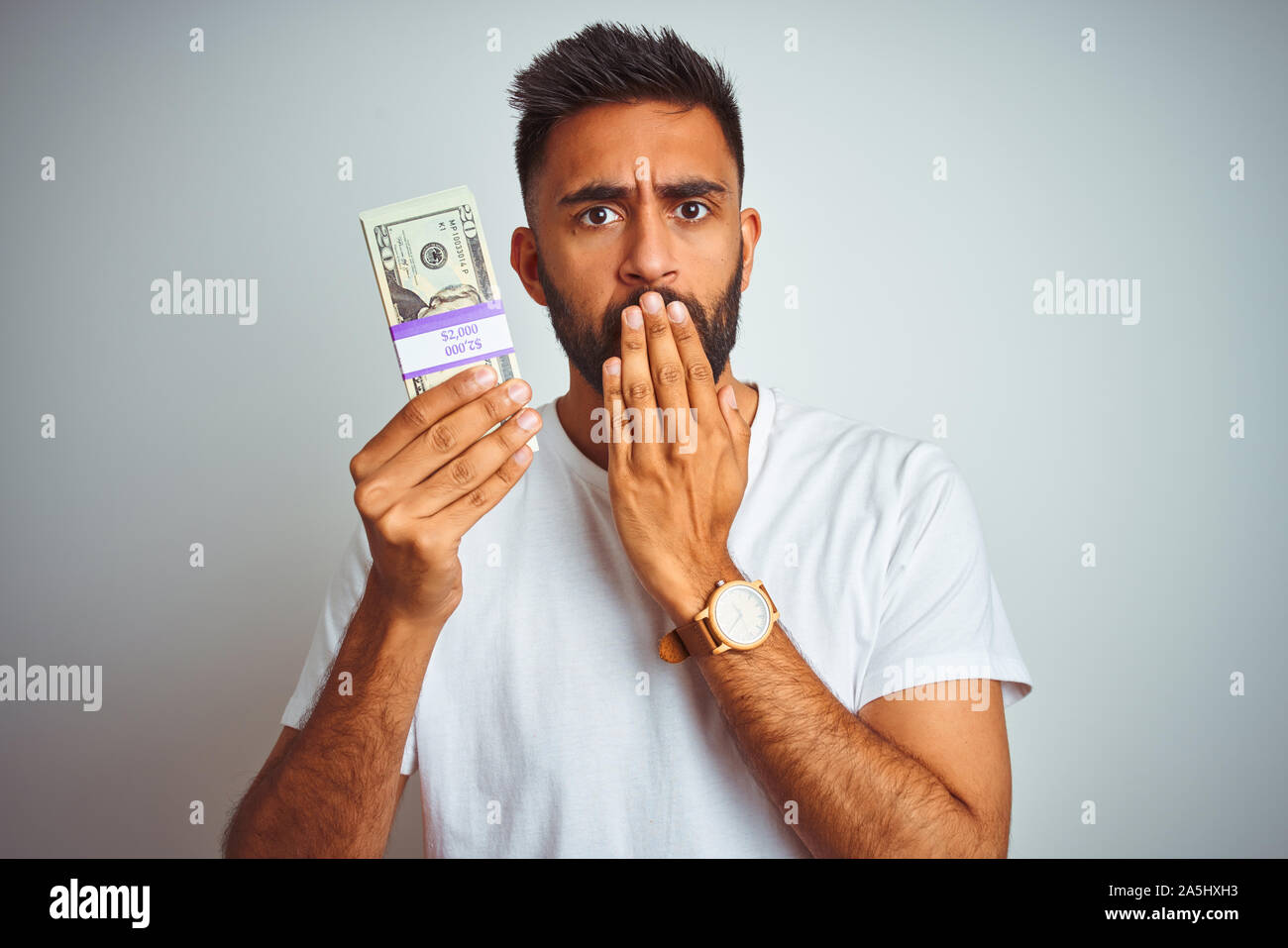 Young indian man holding dollars standing over isolated white ...