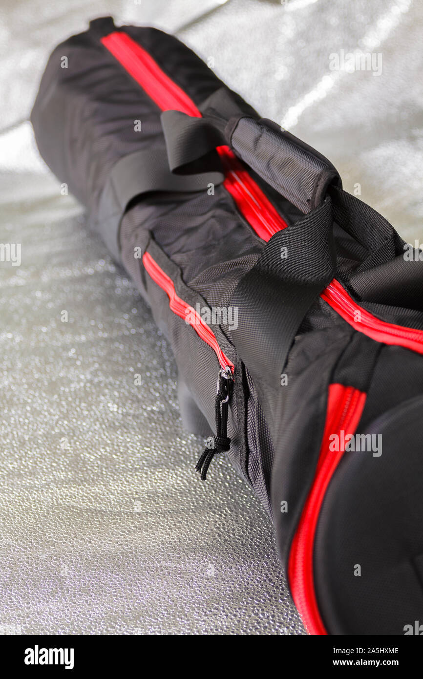 Black photographic tripod case with spectacular red zipper.Selective focus with shallow depth of field. Stock Photo