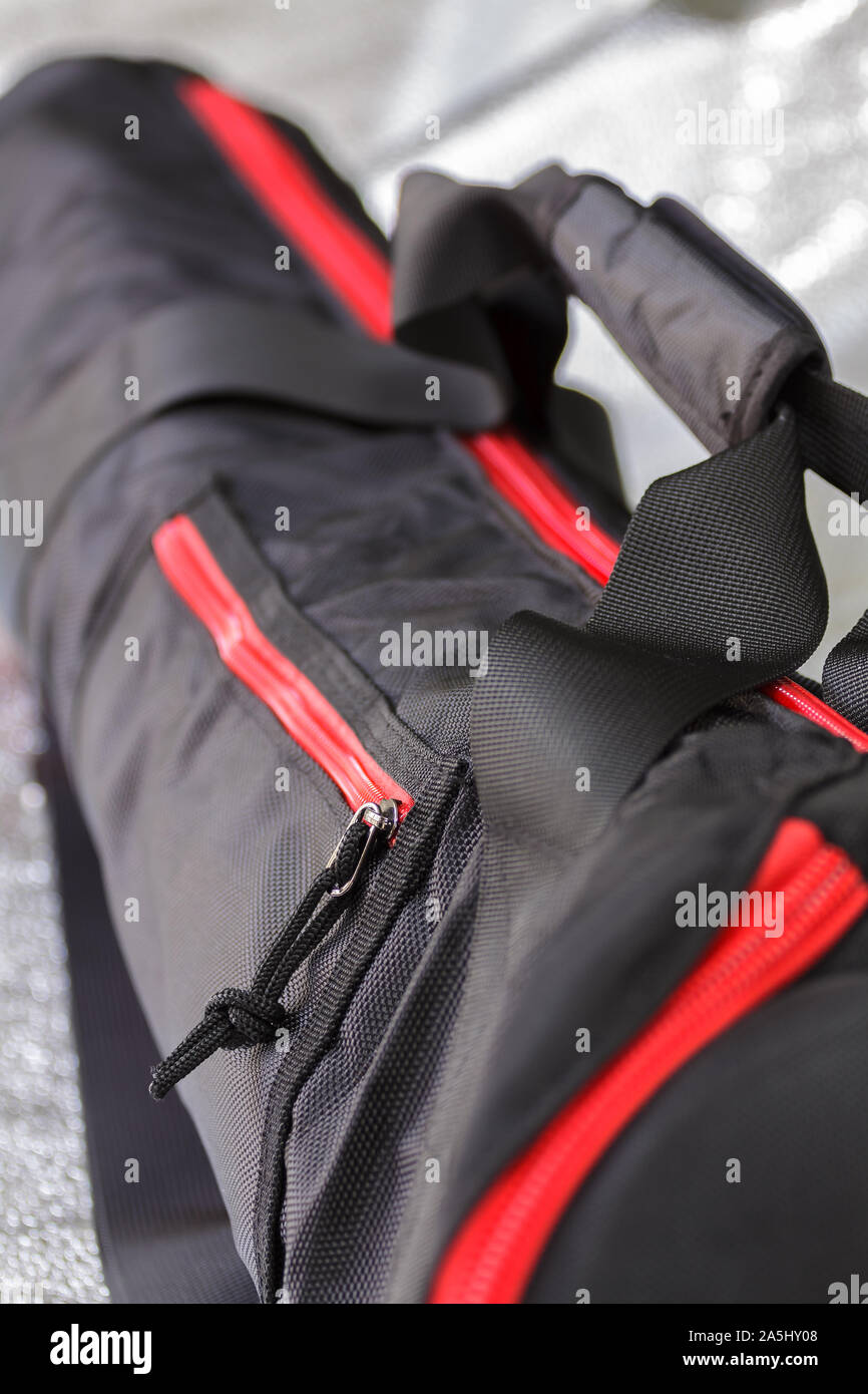 Black photographic tripod case with spectacular red zipper.Selective focus with shallow depth of field. Stock Photo