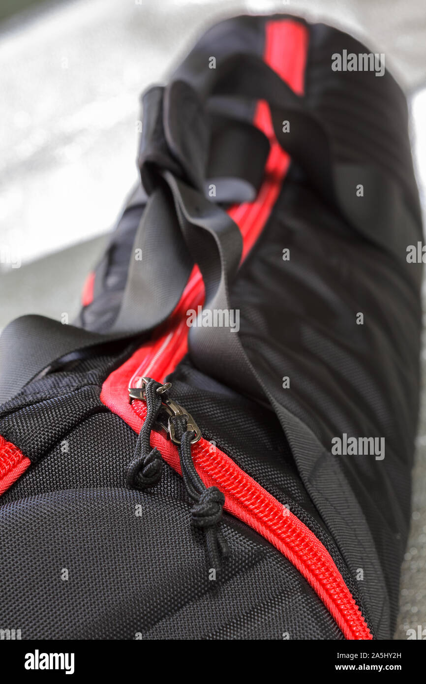 Black photographic tripod case with spectacular red zipper.Selective focus with shallow depth of field. Stock Photo