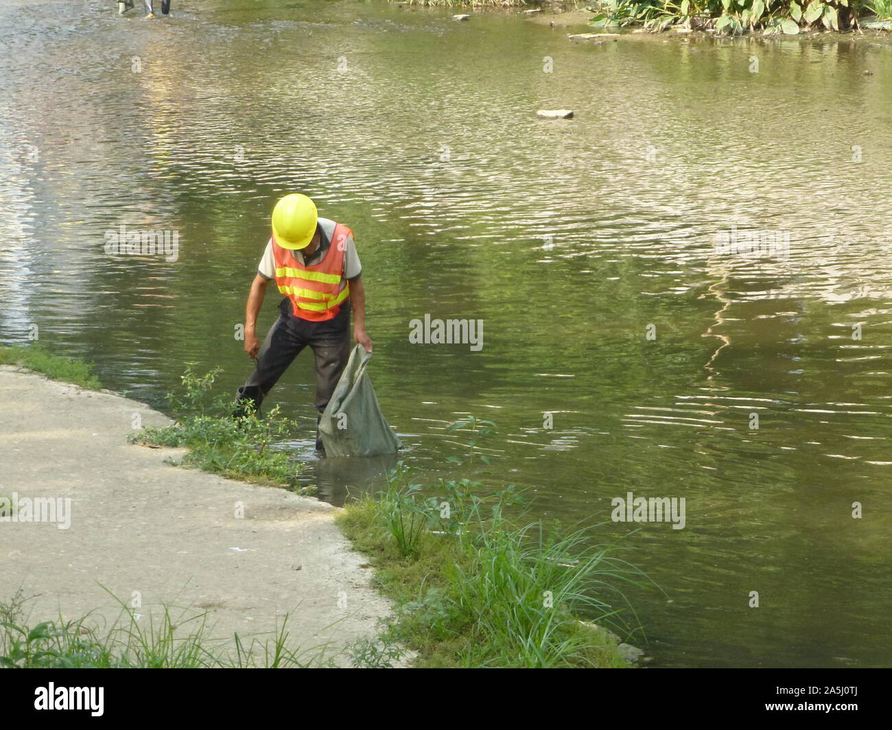 Sanitation workers clean up rubbish in rivers, in Xixiang River ...