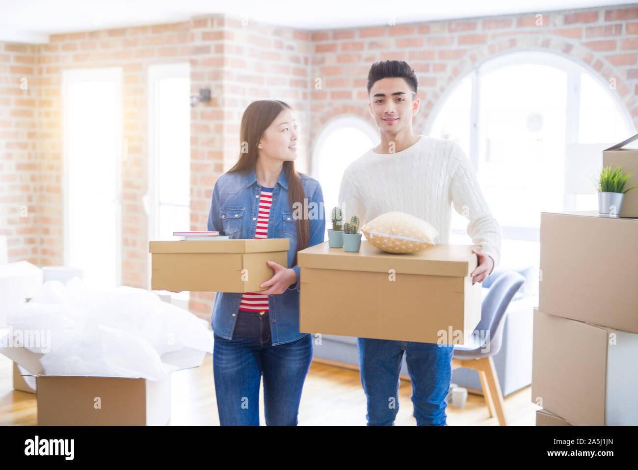 Beautiful young asian couple looking happy holding cardboard boxes ...