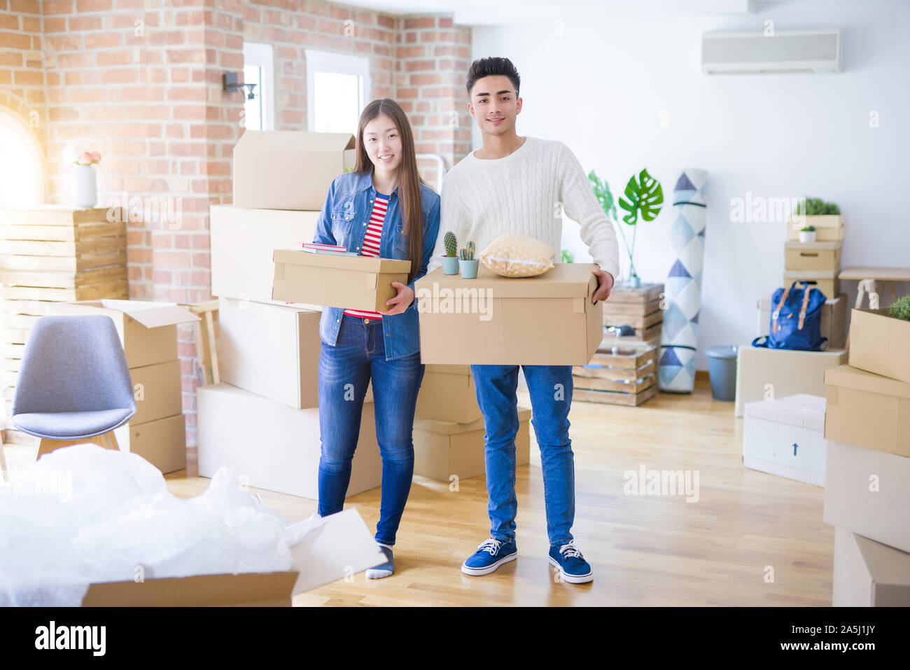 Beautiful young asian couple looking happy holding cardboard boxes ...