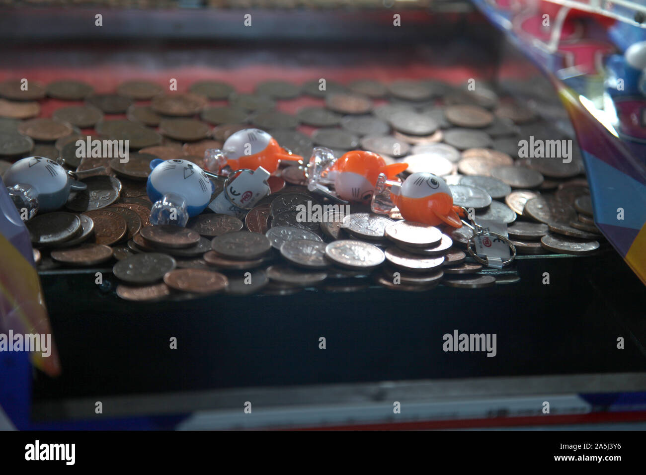 2p coins stacked inside a tuppenny nudge (tipping point) machine at seaside amusement arcade, vintage coin-operated slider game, 2019 Stock Photo