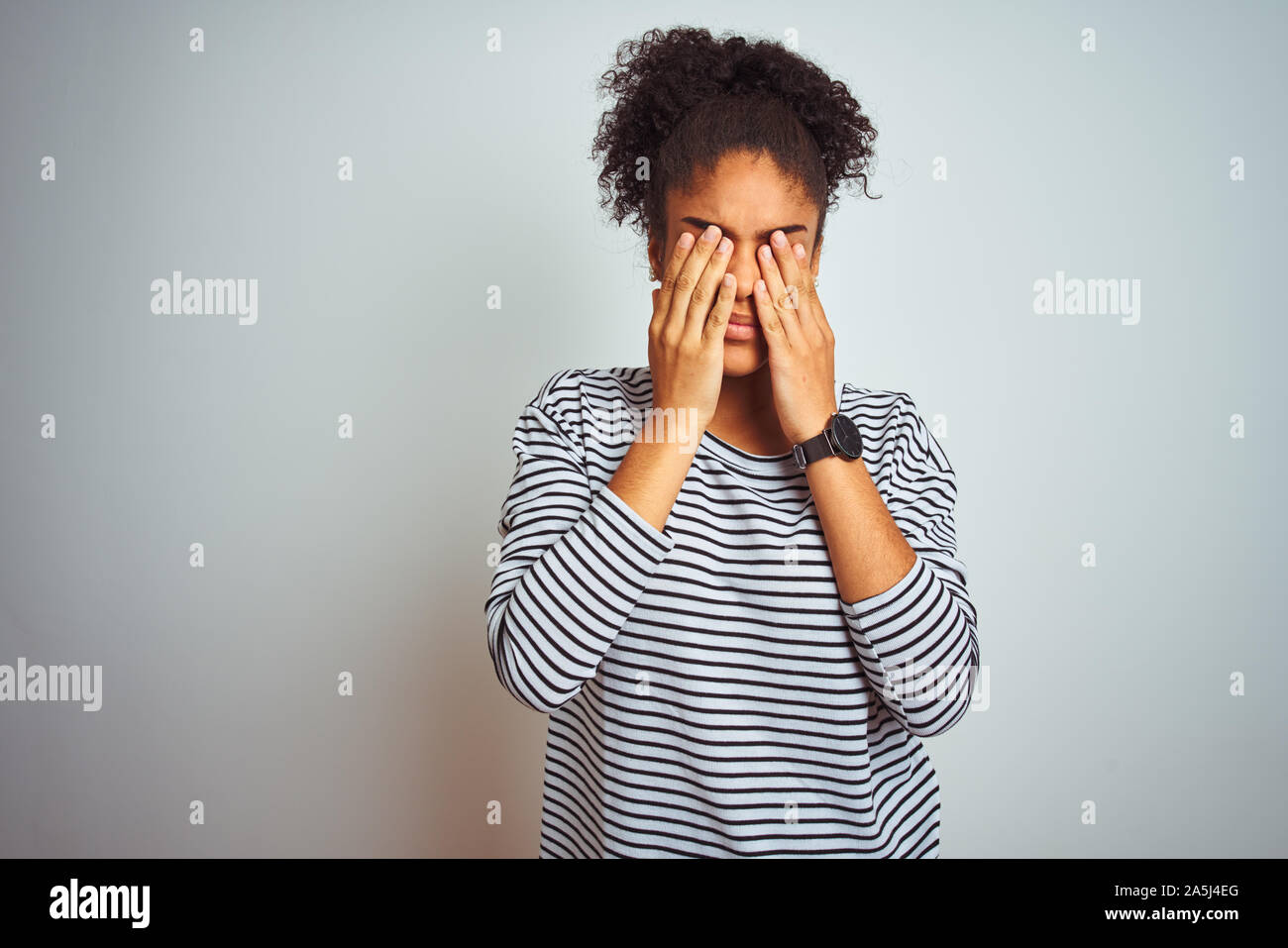 African american woman wearing navy striped t-shirt standing over isolated white background rubbing eyes for fatigue and headache, sleepy and tired ex Stock Photo