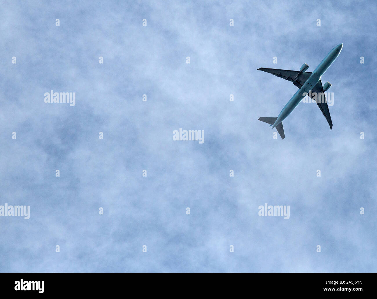 A twin engined jet airliner flying against a patchy blue cloud sky. Stock Photo