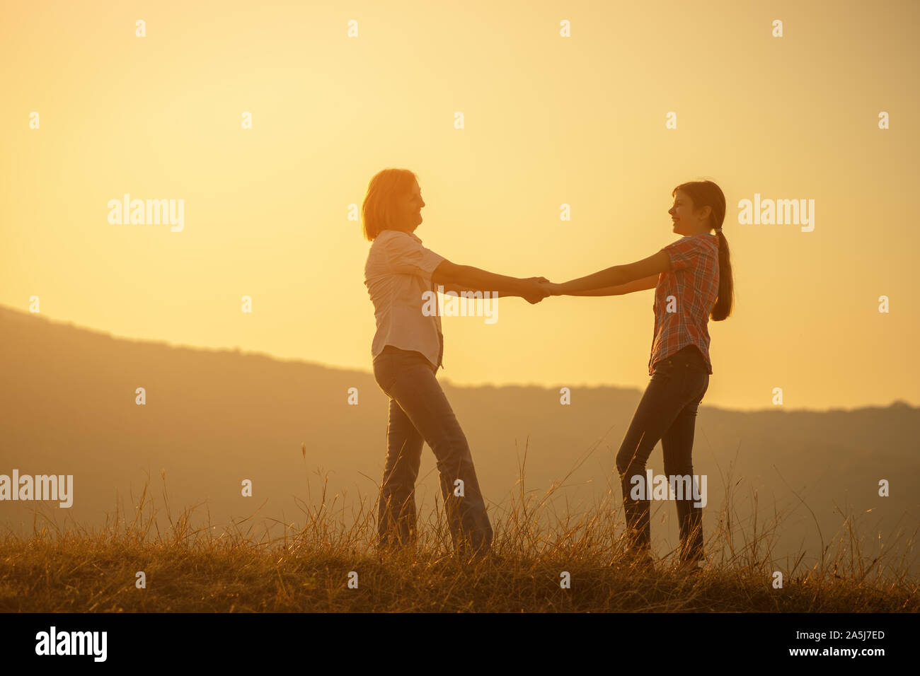 Happy family enjoying sunset. Grandmother and granddaughter holding ...