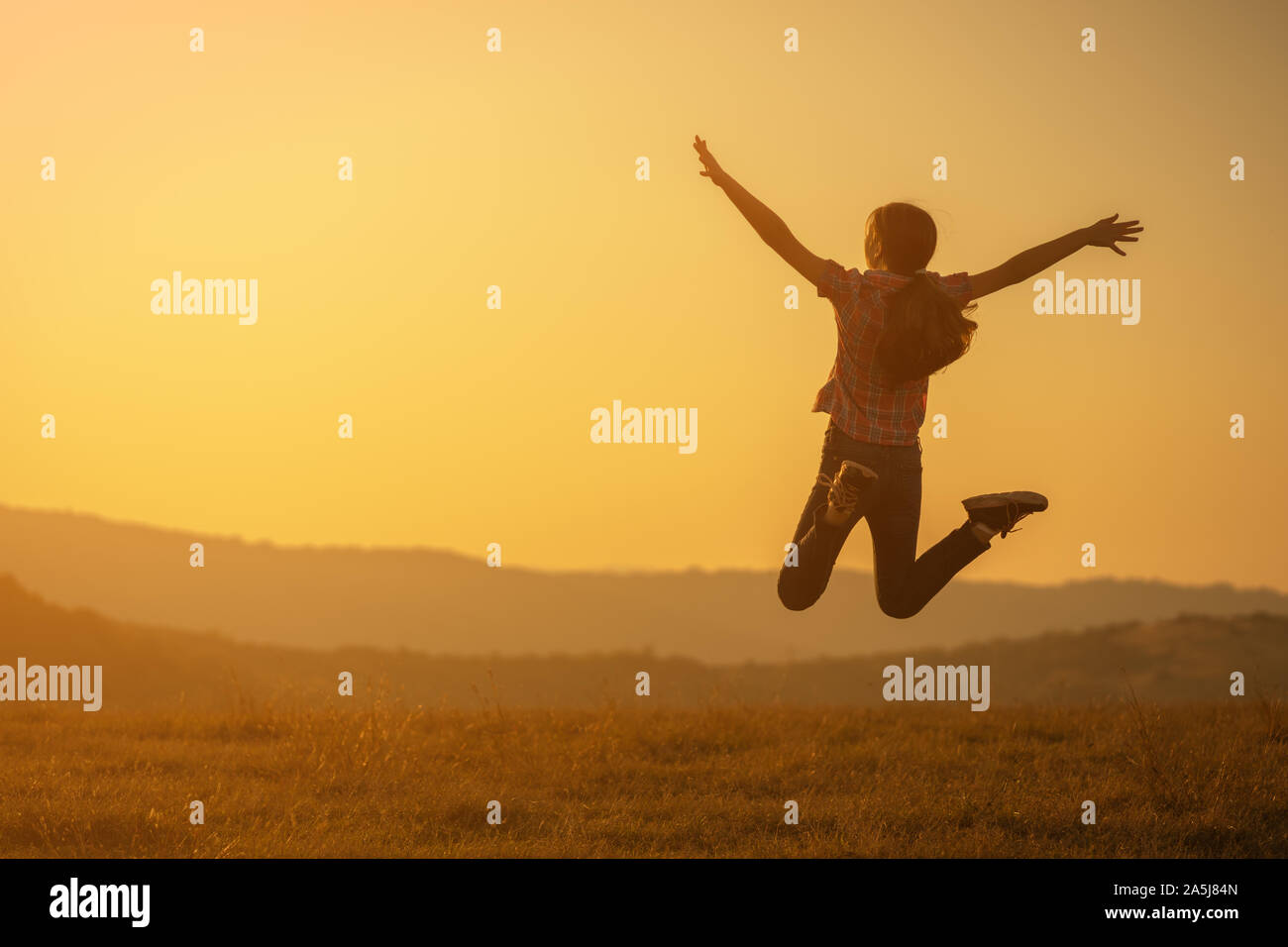 Happy child jumping in nature in sunset. Stock Photo