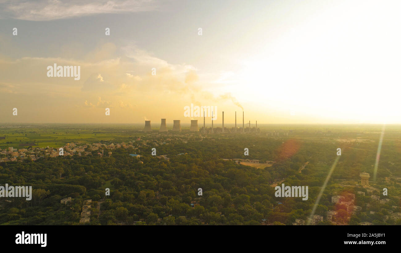 Aerial view of coal power plant -Smoke from Factory Chimnys - Sunrise at green covered city with factories outside the city, Raichur, India Stock Photo
