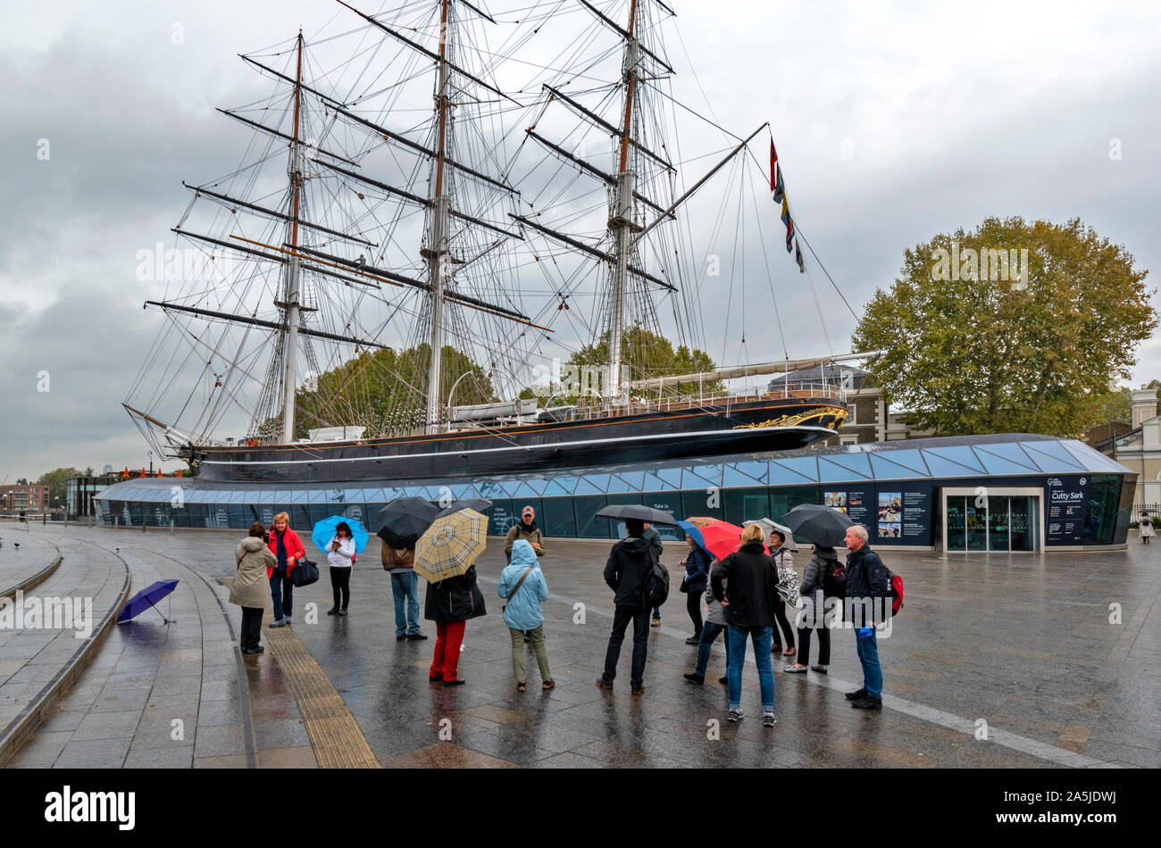 LONDON GREENWICH THE CUTTY SARK CLIPPER AND TOURISTS WITH UMBRELLAS IN THE RAIN Stock Photo
