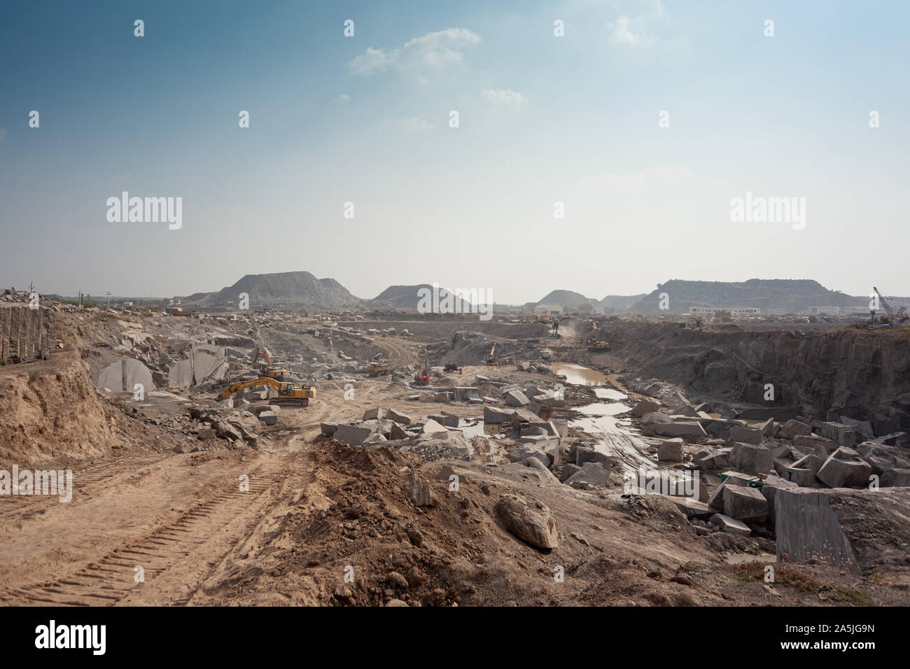 Wide-angle view of a large open-air black galaxy granite quarry. A road runs through it for overburden removal. Ongole, Andhra Pradesh, india Stock Photo