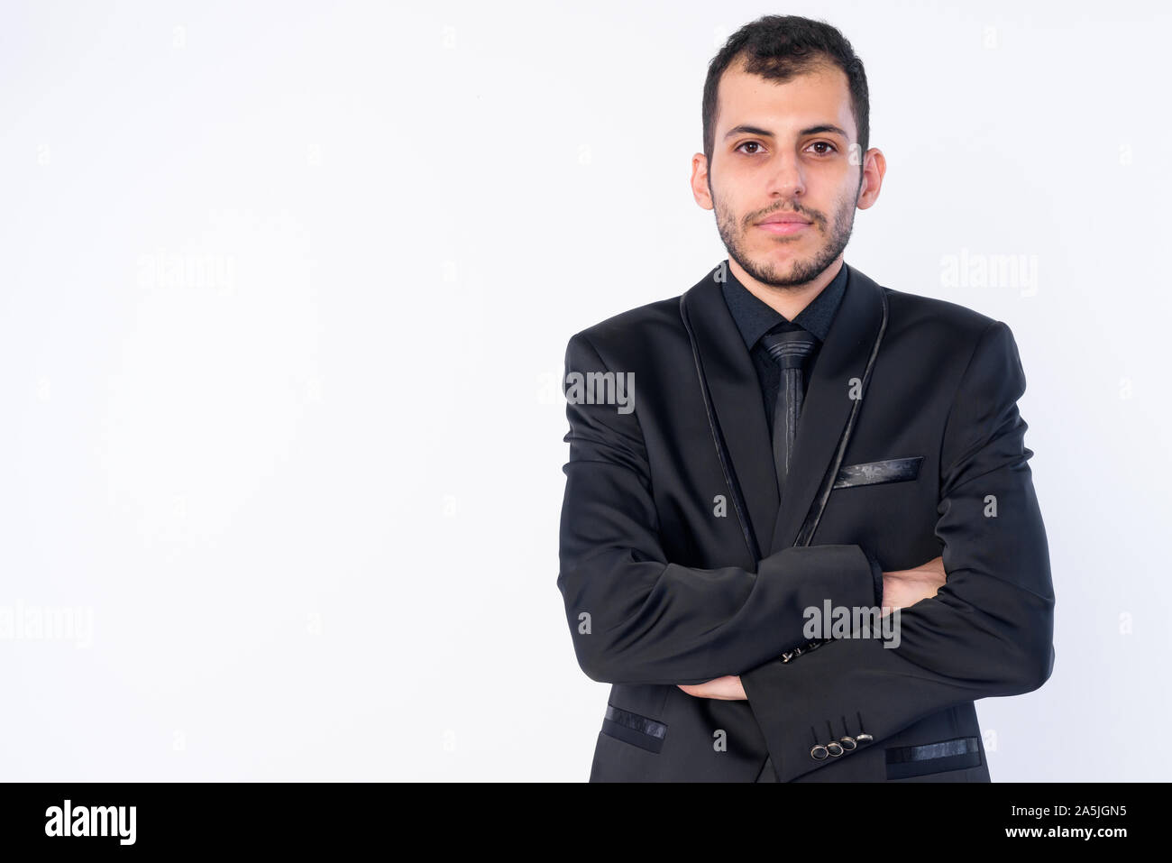 Portrait of young bearded Persian businessman in suit with arms crossed ...
