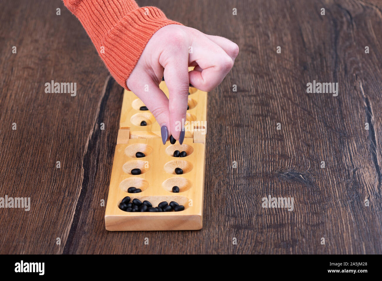 The girl makes a move in the game mankala. The concept of board games. Stock Photo