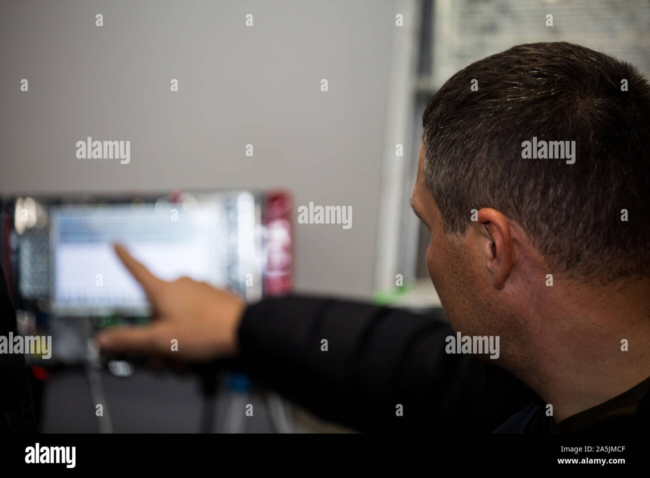 Male engineer reaches touch screen of a controlling console at Petrol Station near Kiev, as specialists install remote fuels gaging system. Stock Photo