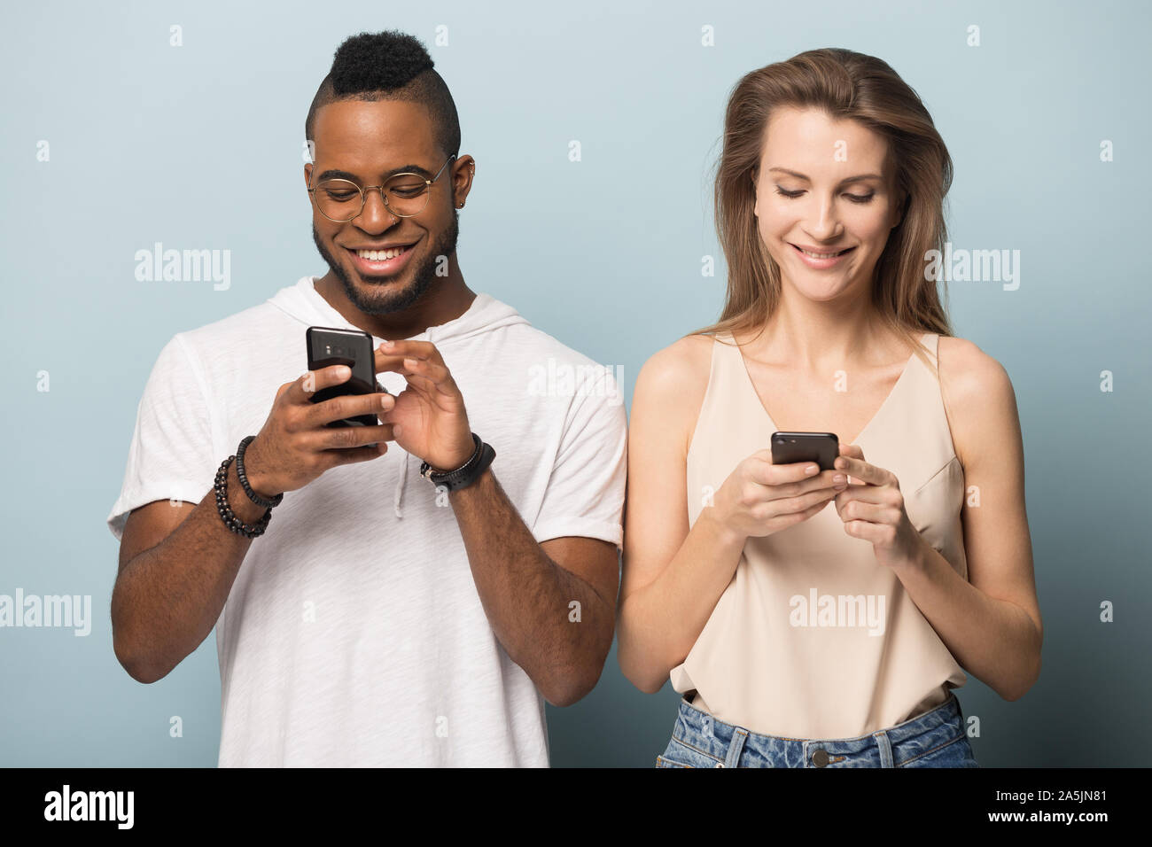 Smiling multiracial couple using modern smartphones internet connection Stock Photo