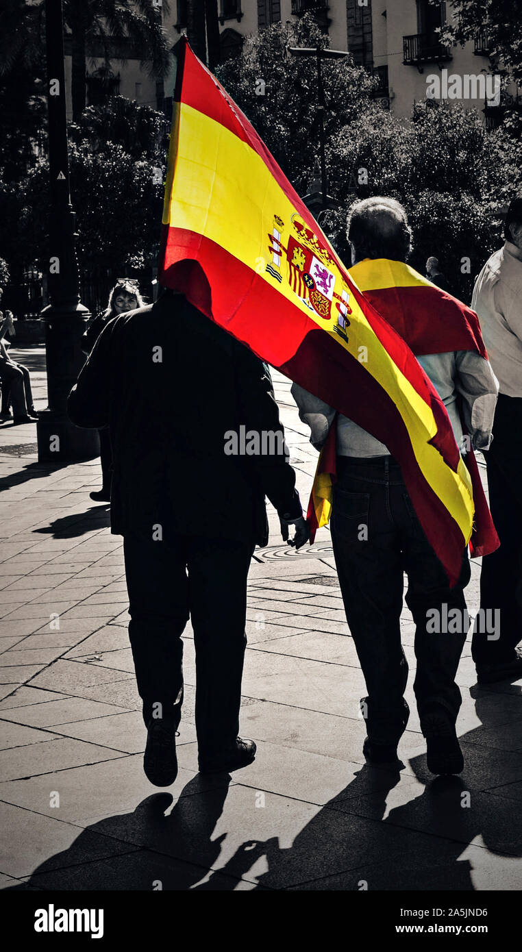 Two anti-separatist men holding the spanish flag in the streets of Seville Stock Photo