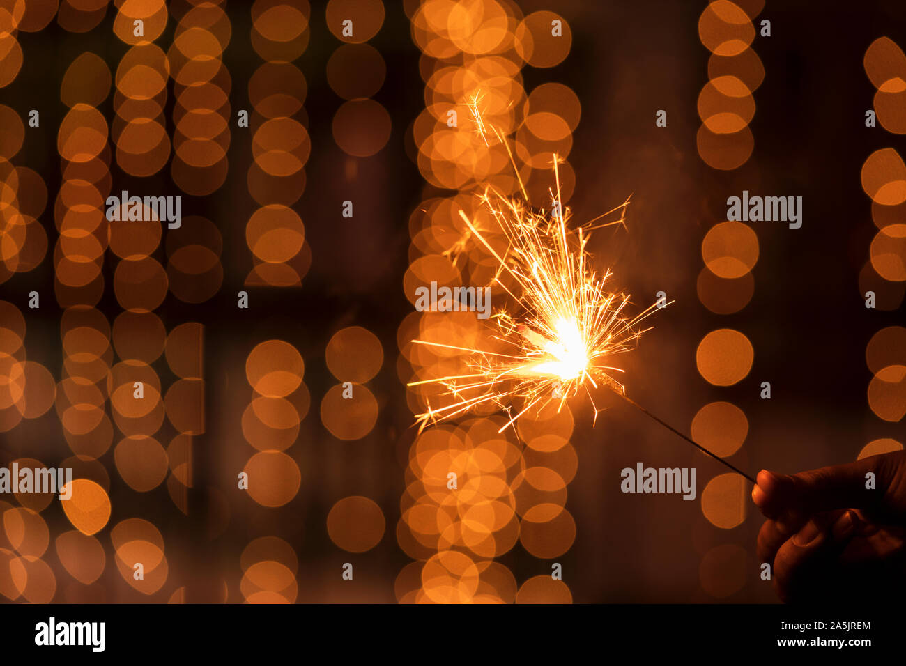 Abstract Sparkelrs background with light yellow bokeh, bright festive Diwali, Christmas, Happy New Year background stock image. Man Holding Sparkler. Stock Photo